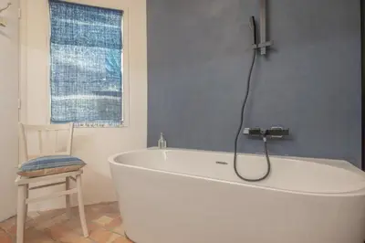 a bath tub in a bathroom with a chair at Artist's House In The Heart Of Lourmarin in Lourmarin