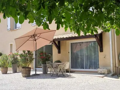 a table and chairs with an umbrella in front of a house at Gîtes de la Coupière Le Mûrier in Aubenas-les-Alpes