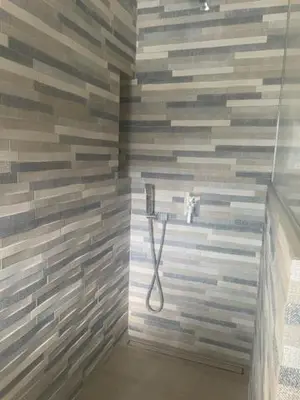 a bathroom with a shower with a tile wall at 1 Brin à part in Maubec