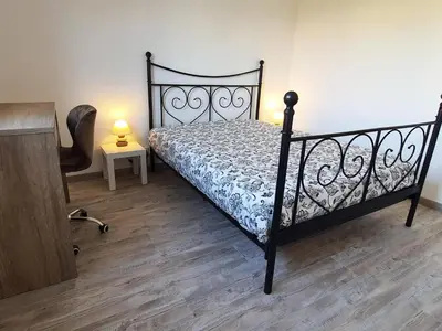 a bedroom with a black bed and a wooden floor at Appartement Spacieux avec Balcon in Carpentras