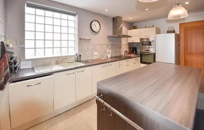 a kitchen with white cabinets and a clock on the wall at Maison Avec Piscine 1 in Mormoiron