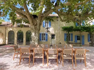 a wooden table and chairs in front of a tree at Le Mas des Poètes in Saint-Andiol
