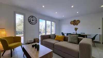 a living room with a couch and a clock on the wall at Villa Quercus Design Piscine et Loisirs in Ménerbes