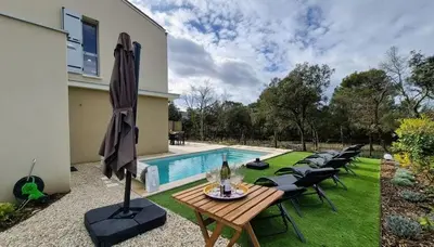 a patio with a table and chairs next to a pool at Villa Quercus Design Piscine et Loisirs in Ménerbes