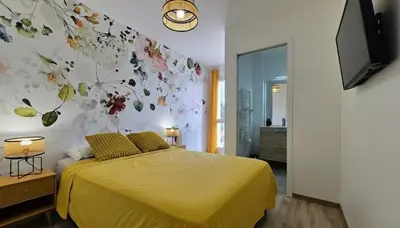 a bedroom with a yellow bed with a flower wall at Villa Quercus Design Piscine et Loisirs in Ménerbes
