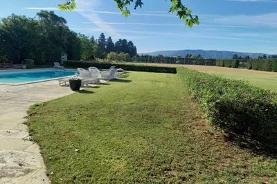 a glass table with pink cushioned chairs on a patio at Villa Ulysse - Tennis court and private pool in LʼIsle-sur-la-Sorgue