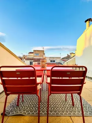 two red benches sitting next to a table on a balcony at Rare duplex with rooftop terrace in Aix-en-Provence