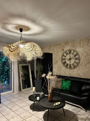 a living room with a couch and a clock on the wall at Les hirondelles Piscine privée climatisation billard calme 4 lits in LʼIsle-sur-la-Sorgue