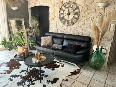 a living room with a black leather couch and a table at Les hirondelles Piscine privée climatisation billard calme 4 lits in LʼIsle-sur-la-Sorgue