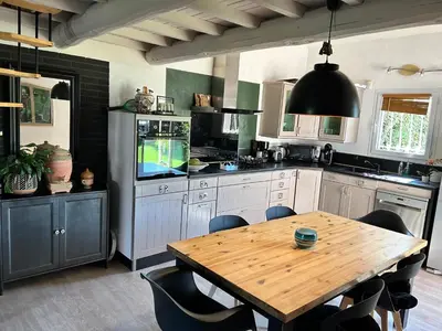 a kitchen with a wooden table and a dining room at Les hirondelles Piscine privée climatisation billard calme 4 lits in LʼIsle-sur-la-Sorgue