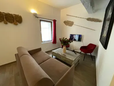 a living room with a couch and a red chair at Location grand studio centre ville Isle sur la sorgue in LʼIsle-sur-la-Sorgue