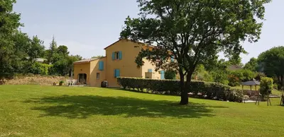 a house in a field with a tree in the foreground at Dépendance de charme avec piscine en luberon in Peypin-dʼAigues