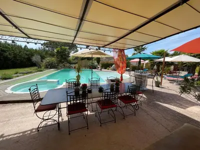 a patio with a table and chairs and a swimming pool at Le Mas de la Butte Blanche in Orgon