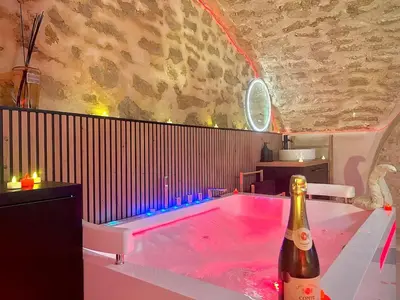a hot tub in a room with a bottle of champagne at Secret LoveRoom - SpaBalnéo, Lit King Size, CLIM, Chic, calme et discret, 2 personnes in Saint-Chamas