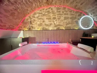 a bath tub filled with pink water in a room at Secret LoveRoom - SpaBalnéo, Lit King Size, CLIM, Chic, calme et discret, 2 personnes in Saint-Chamas
