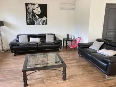 a living room with a black leather couch and a table at gite de charme au pied du luberon avec piscine privée à Apt en Provence in Apt