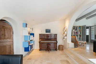 a living room with a piano and a book shelf at Aurenza - Piscine - Jardin paysager - Vue campagne in Éguilles