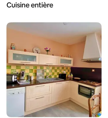 a kitchen with white cabinets and green tiles on the wall at Maison provençale in Céreste