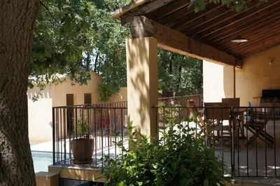 a patio with a fence and a table and chairs at Villa avec vue au pied du Luberon in Maubec
