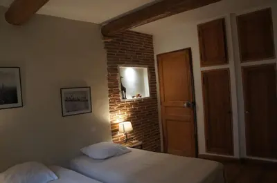 a bedroom with two beds and a brick wall at Villa avec vue au pied du Luberon in Maubec