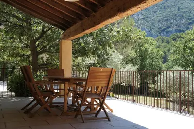 a wooden table and chairs sitting on a patio at Villa avec vue au pied du Luberon in Maubec