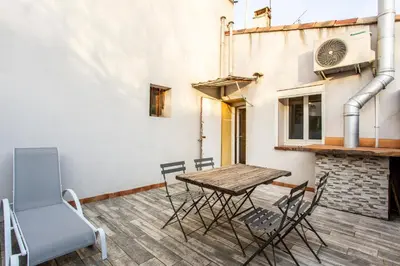 a patio with a wooden table and chairs on a building at L'Oustaou - Climatisé avec terrasse in Pélissanne
