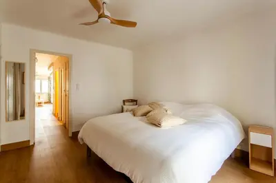 a bedroom with a white bed with a ceiling fan at L'Oustaou - Climatisé avec terrasse in Pélissanne