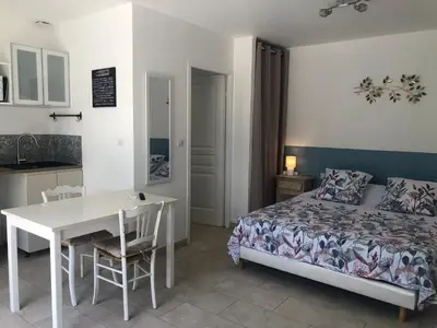 a bedroom with a bed and a table and a kitchen at La Cigale et la Fourmi in Les Taillades