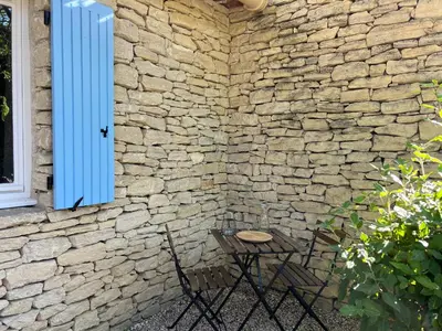 a table and chairs in front of a stone wall at Jolie maison avec piscine à Gordes in Gordes