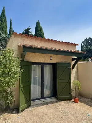 a garage with green doors in front of a house at COZY LOFT - Maisonnette esprit loft in Saint-Cannat