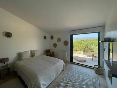 a bedroom with a large bed and a large window at Villa contemporaine avec piscine - 5 min de Gordes - vue sur le Luberon in Cabrières-dʼAvignon