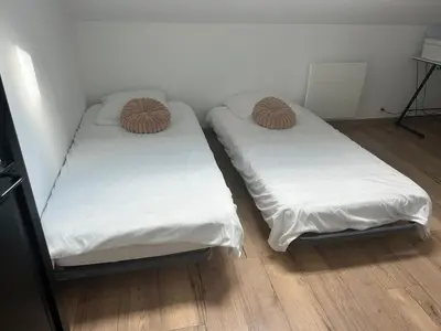 two beds in a room with white sheets and brown pillows at Villa moderne tout confort in Salon-de-Provence