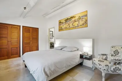 a white bedroom with a bed and a chair at La Bastide des Plâtrières in La Roque-sur-Pernes