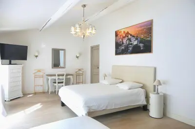 a white bedroom with two beds and a table at La Bastide des Plâtrières in La Roque-sur-Pernes
