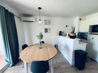 a dining room table with chairs and a kitchen at Appartement Domaine du Golf de Pont Royal in Mallemort