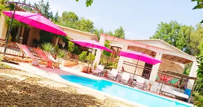 a house with pink umbrellas and a swimming pool at Maison Maïtri in Lauris
