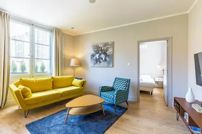 a living room with a yellow couch and a blue rug at Appartement centre ville, Air Conditionné, 2 suites, parking sur demande in Aix-en-Provence