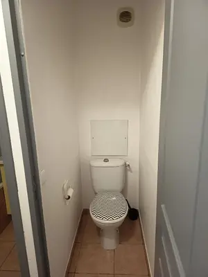 a bathroom with a toilet with a black and white lid at Golf de pont royal in Mallemort