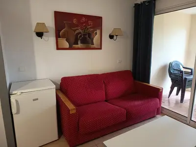 a living room with a red couch and a refrigerator at Golf de pont royal in Mallemort