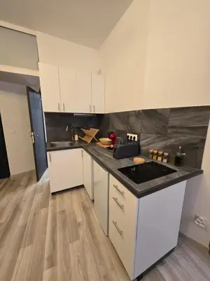 a kitchen with white cabinets and a black counter top at Studio Vacances super équipé in Carpentras