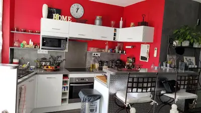 a kitchen with red walls and white cabinets at Maison de charme in Pierrevert