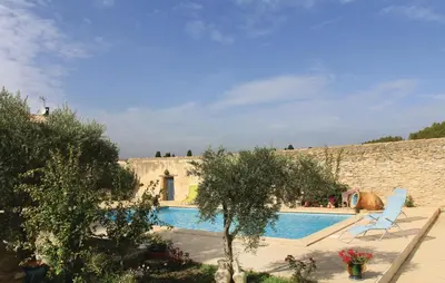 a swimming pool with two lounge chairs next to a stone wall at Beautiful Home In Lancon De Provence in Lançon-Provence