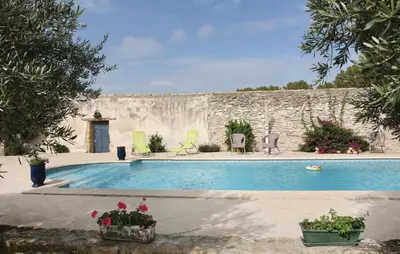 a swimming pool with chairs and a stone wall at Beautiful Home In Lancon De Provence in Lançon-Provence