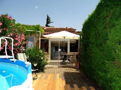 a backyard with a pool and a house with an umbrella at Duplex En Provence in Vedène