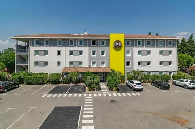 a large building with a parking lot in front of it at B&B HOTEL Salon de Provence in Salon-de-Provence