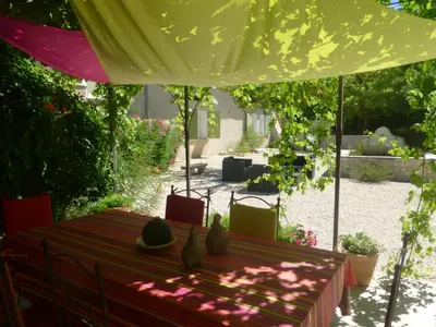 a table under a yellow umbrella in a garden at B&B Les Argiles in Mérindol