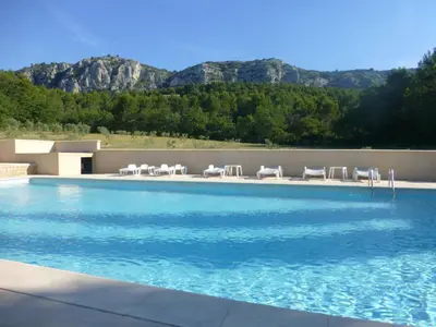 a swimming pool with chairs and mountains in the background at B&B Les Argiles in Mérindol