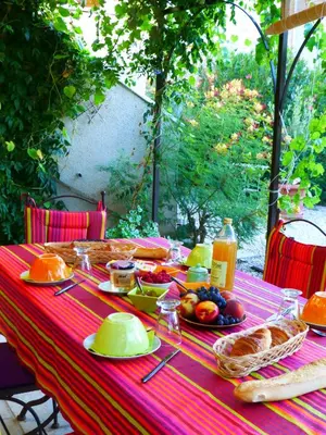 a table with a red table cloth with food on it at B&B Les Argiles in Mérindol