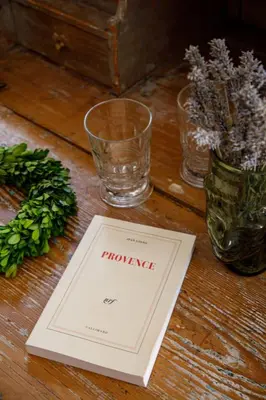 a book sitting on a table with glasses and flowers at La Magnanerie de l'Isle B&B in LʼIsle-sur-la-Sorgue