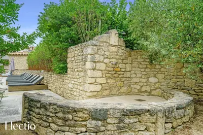 a stone wall with a fire pit in a yard at Résidence Les Petitons in Oppède